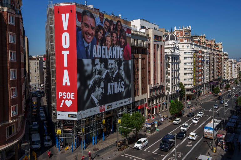 Une affiche électorale géante représentant le Premier ministre espagnol et candidat du PSOE Pedro Sanchez, le chef du parti conservateur PP Alberto Nunez Feijoo et le chef du parti d'extrême droite VOX Santiago Abascal est suspendu à un bâtiment de l'avenue Gran Via à Madrid