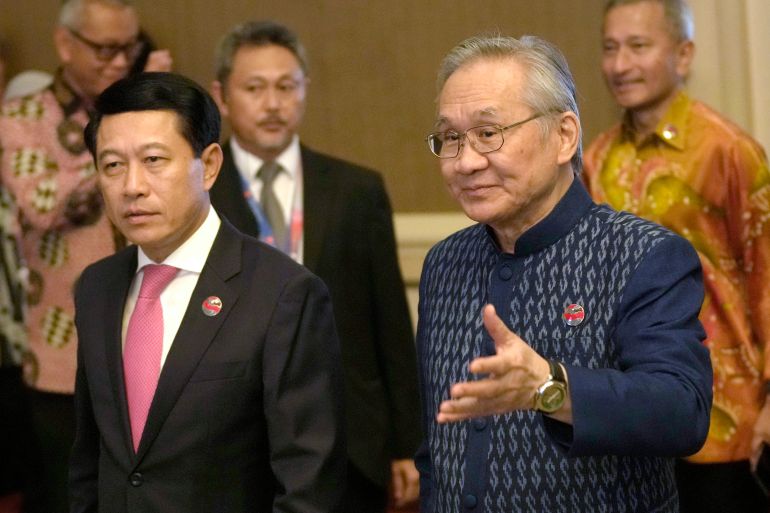 Thailand's Foreign Minister Don Pramudwinai walking with his Lao counterpart at the ASEAN summit. He is smiling and gesturing with his left hand