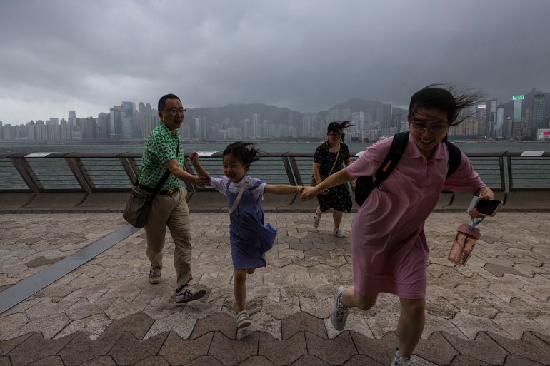 Mainland Chinese tourists run along a promenade during a typhoon in Hong Kong, Monday, July 17, 2023.