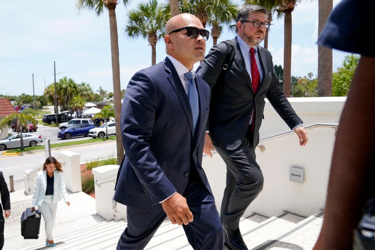 Een kale man in pak loopt de trap op naar een gerechtsgebouw in Miami.