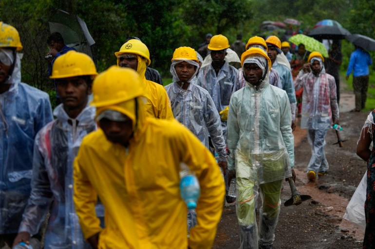 Rescuers walk to the site of a landslide in Riggad district, western Maharashtra state, India, Thursday, July 20, 2023.