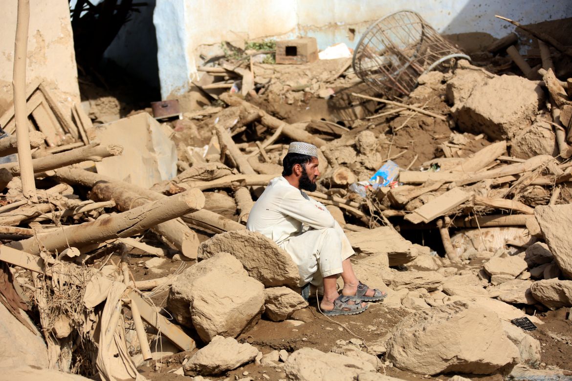 A man sits near his damaged house after heavy flooding in the Maidan Wardak province