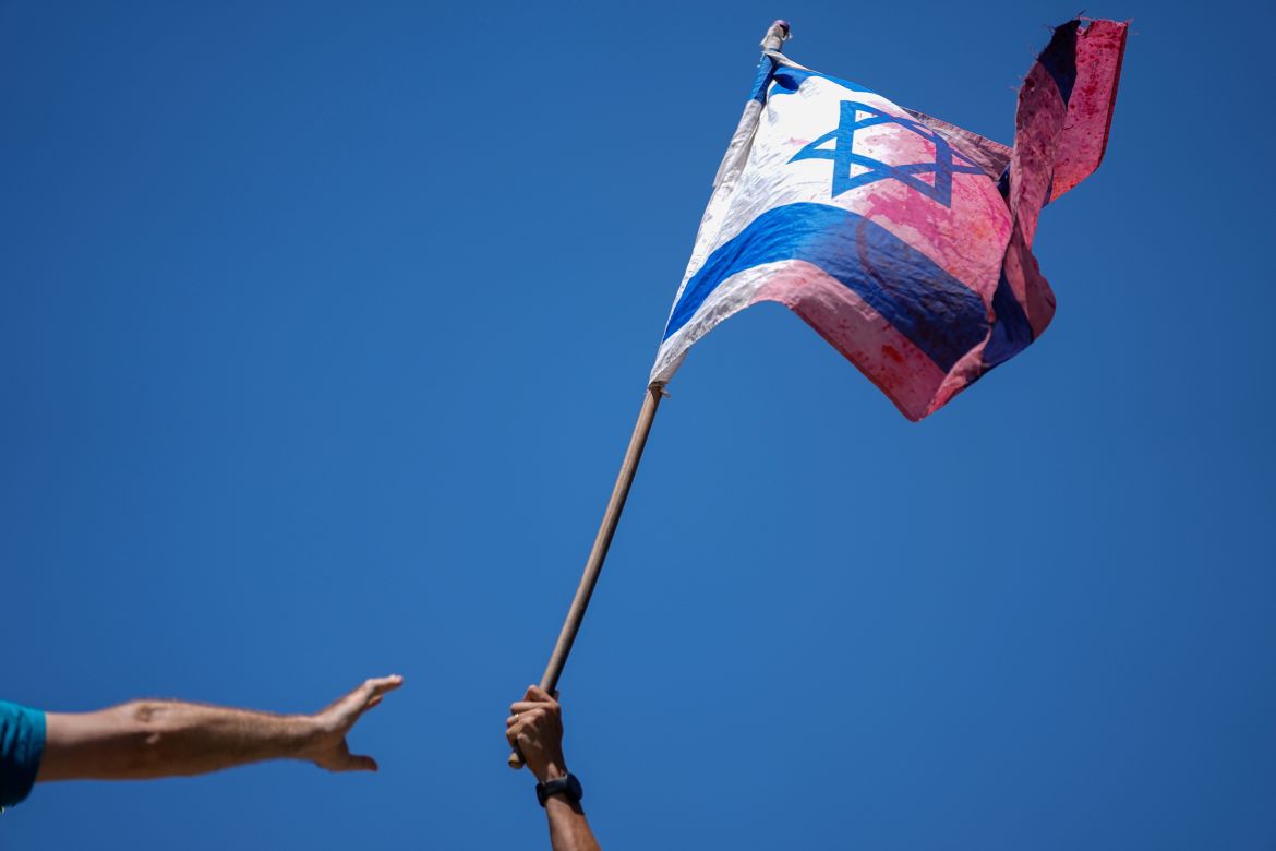 A demonstrator waves a colored Israeli flag during a protest
