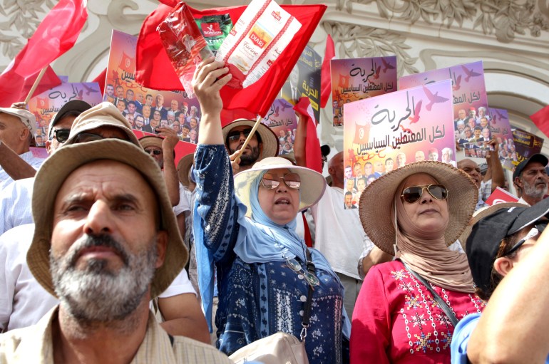 Tunisians demonstrate against Tunisian President Kais Saied during the Tunisian Republic Day in Tunis, Tunisia, Tuesday, July 25, 2023. The sign reads in Arabic: "Freedom for all political prisoners". (AP Photo/Hassene Dridi)