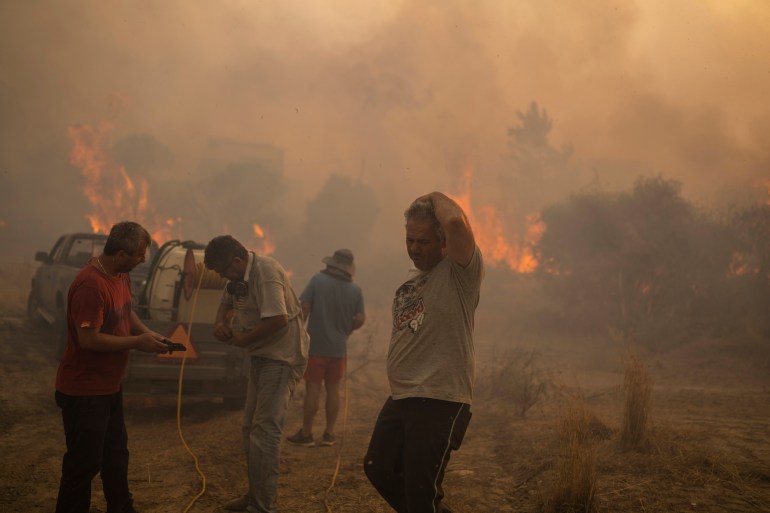 Penduduk setempat berusaha memadamkan api yang membakar di desa Gennadi, di pulau Rhodes di Aegean