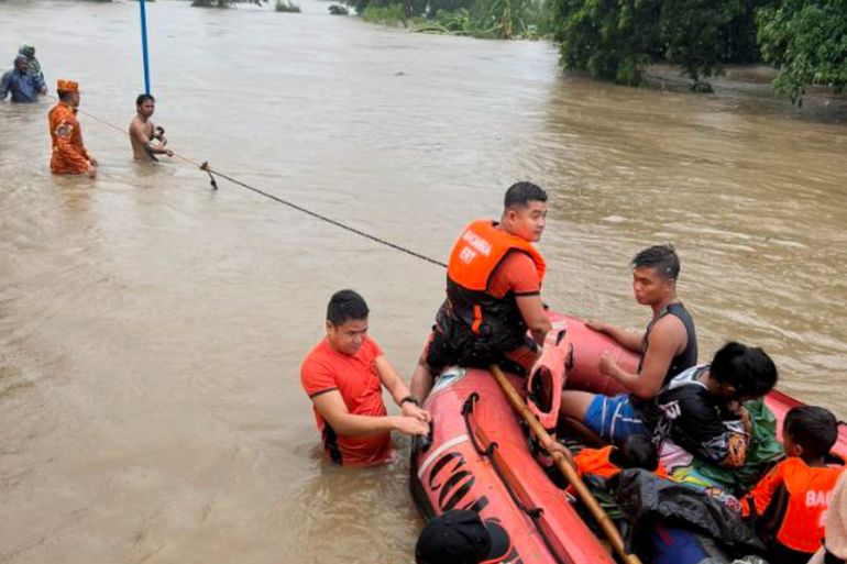 Rescuers use a rubber boat along floodwaters caused by Typhoon Doksuri as they evacuate residents to higher grounds in Bacarra, Ilocos Norte province, northern Philippines on Wednesday July 26, 2023.