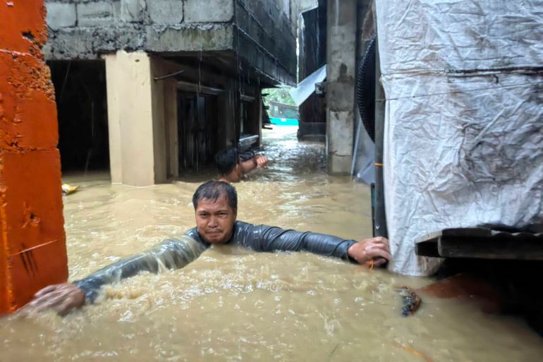 A man negotiates neck-deep floodwaters in his village caused by Typhoon Doksuri in Laoag city, Ilocos Norte province, northern Philippines