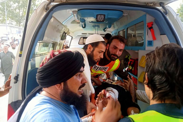 In this photo provided by Rescue 1122 Head Quarters, rescue workers carry a wounded man after a bomb explosion in the Bajur district of Khyber Pakhtunkhwa