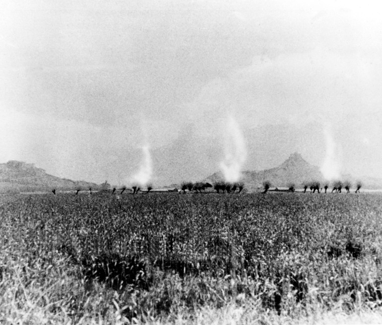 Columns of smoke rising as Chinese soldiers push into Lhasa in 1959. The Potala Palace is behind obscured by dust and smoke. The picture is in black and white and quite grainy.