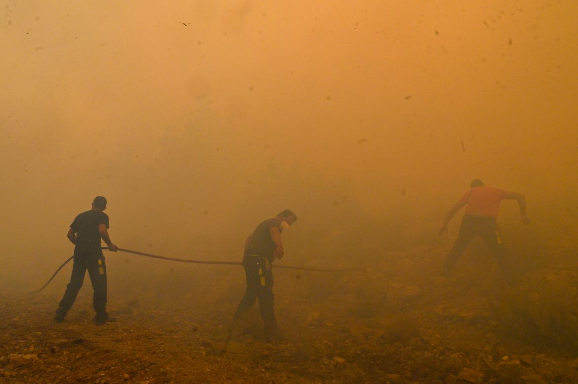 Locals help firefighters as they try to extinguish a wildfire burning near the village Vlyhada near Athens