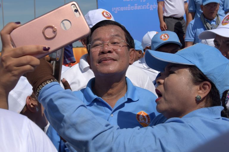Cambodia's Prime Minister Hun Sen (C) poses for selfies with supporters of the Cambodian People's Party (CPP) on the last day of the commune election campaign in Phnom Penh on June 2, 2017. - A sea of pro-government supporters rallied in the Cambodian capital in support of strongman PM Hun Sen on June 2, two days before local polls set to test the mettle of an opposition desperate to upend his 32-year rule. (Photo by TANG CHHIN Sothy / AFP)