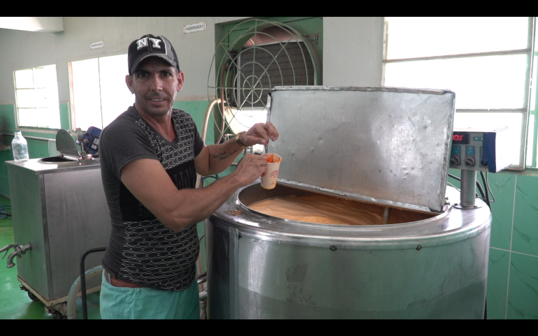 موظف ألبان روجاس يقف لالتقاط صورة بجوار الحليب المبستر والملون صناعيًا