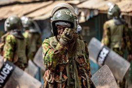 An anti-riot police officer reacts to the effects of tear gas after confronting protesters during anti-government protests in Nairobi.