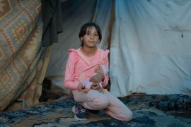 Syrian-born Hisa, 11, stands in front of the tent where she currently lives