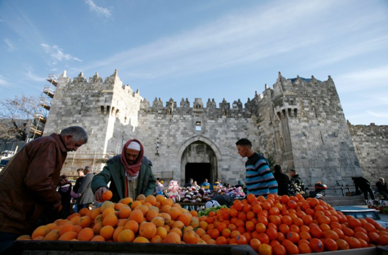 Palestinians select fruit at a stall near Damascus Gate