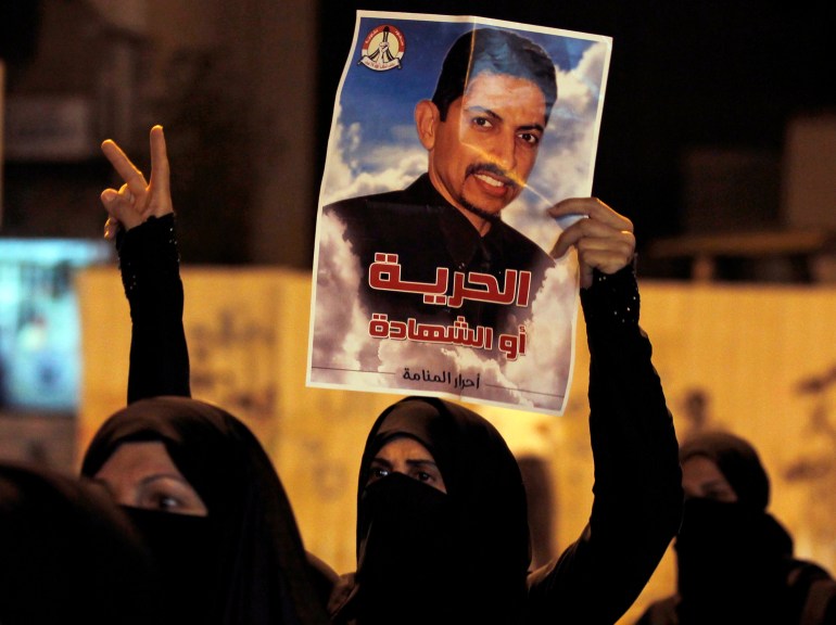 A protester holds a poster of Human Rights Activists Abdulhadi al-Khawaja during an anti-government rally 
