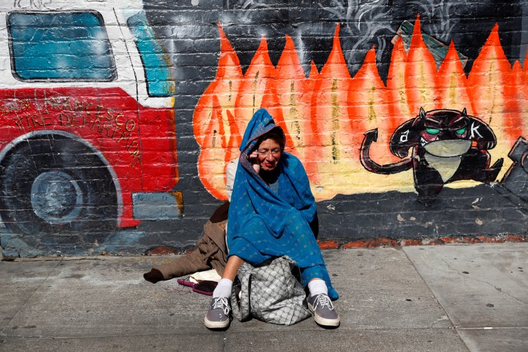 A woman sits with her belongings on the sidewalk in the Tenderloin area of San Francisco, California, U.S.