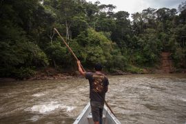 Man standing in canoe traversing river