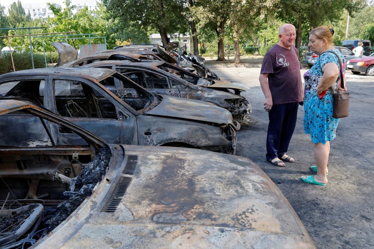 Local residents stand next to cars destroyed by recent shelling in the course of Ukraine-Russia conflict in the Russian-controlled city of Enerhodar in Zaporizhzhia region, Ukraine August 30, 2022. REUTERS/Alexander Ermochenko