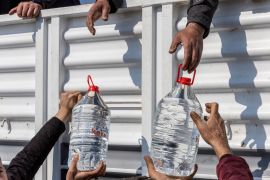 People receive water from aid workers, in the aftermath of the deadly earthquake, in Samandag town of the Hatay province, Turkey