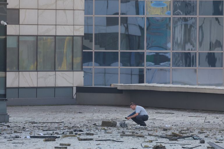 A man checks the debris next to a damaged office building in Moscow following a reported Ukrainian drone attack