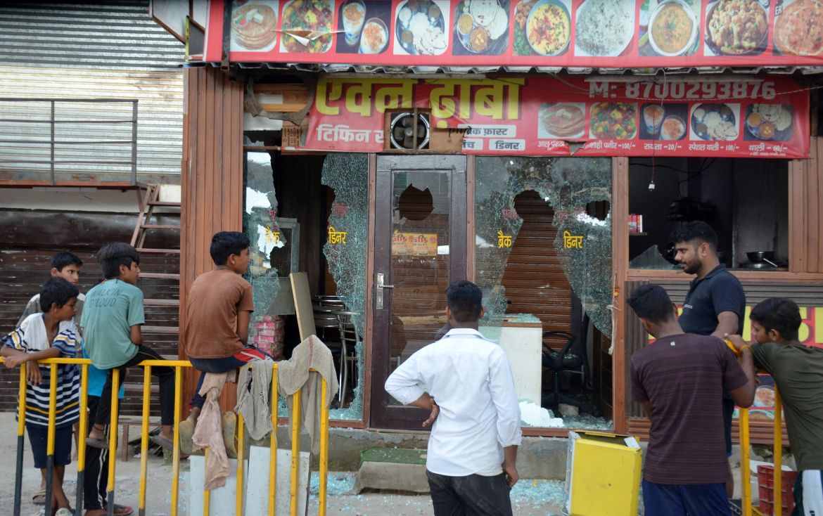 People stand in front of an eatery after it was vandalised