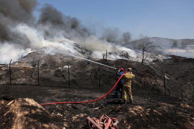 Firefighters try to extinguish a fire burning at a recycling plant, in Sesklo, in central Greece