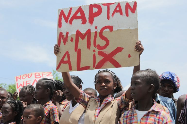 A child holds up a sign reading, 'We're waiting for nurse Alix', during a protest in Port-au-Prince, Haiti, demanding the release of a US nurse and her daughter who were kidnapped