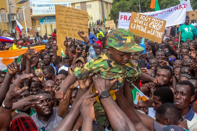 Men hold a child dressed in military uniform as they gather with thousands of anti-sanctions protestors in support of the putschist soldiers in the capital Niamey, Niger August 3, 2023.