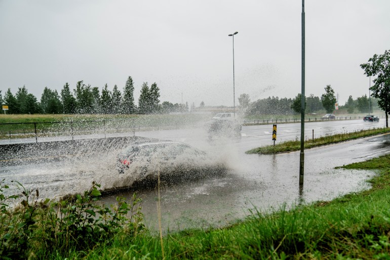 A car drives through floodwater on an exit of the E6 by Klofta north of Oslo, Norway