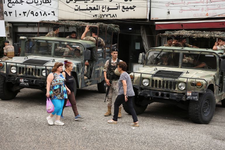 People walk past Lebanese army members that secure the area
