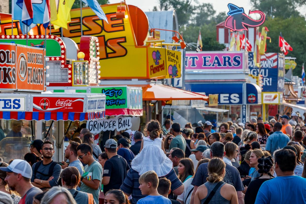 A view over the top of the crowds at the Iowa State Fair, as visitors filter past stalls for food and games.