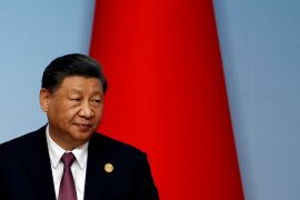 Xi Jinping seated in front of a Chinese flag