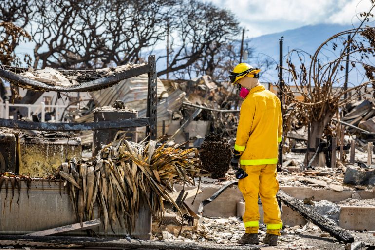 A search-and-rescue team member looks at the damage of wildfires in Lahanai, Maui, US