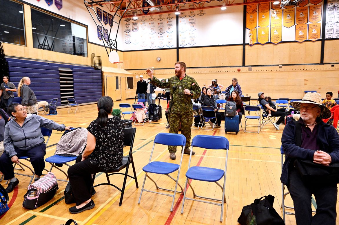 A warrant officer updates people waiting in a school gym to evacuate by plane from Yellowknife, Canada