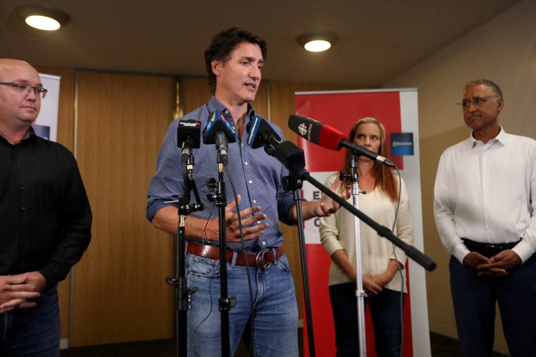Justin Trudeau in denim shirt speaking in front of microphones