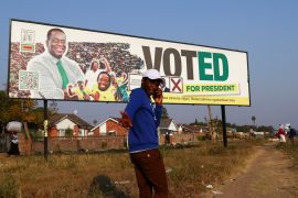 A man walking past a billboard urging people to vote for incumbent Emmerson Mnangagwa