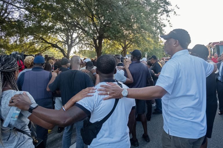 People put their arms around each other's shoulders during a vigil following the Jacksonville racist shooting
