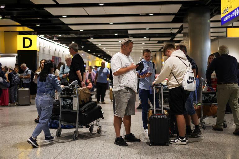 Travellers stand near the British Airways check-in area at Heathrow Terminal 3