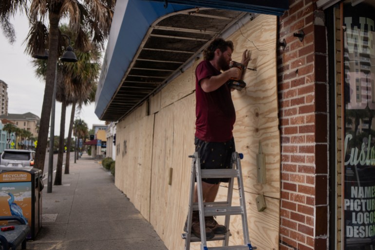 Steve Pizzano helps board up a friend's souvenir shop ahead of the arrival of Hurricane Idalia