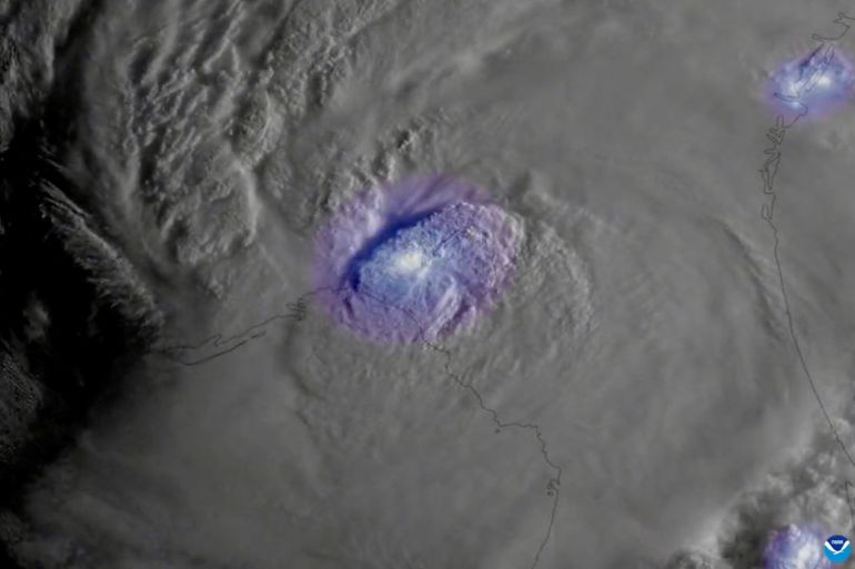 A satellite image of Hurricane Idalia, with a purple glow representing lightning.