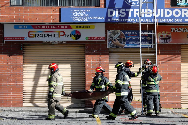 Firefighters carry the remains of a car after an explosion in Quito