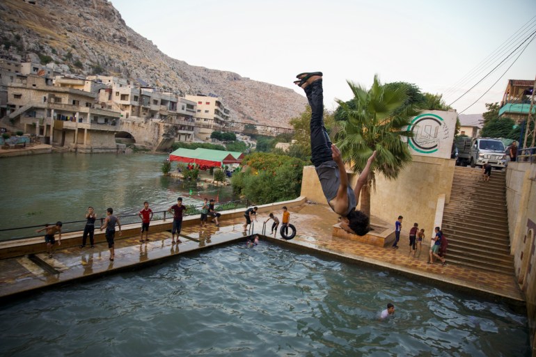A boy does an acrobatic flip into the water