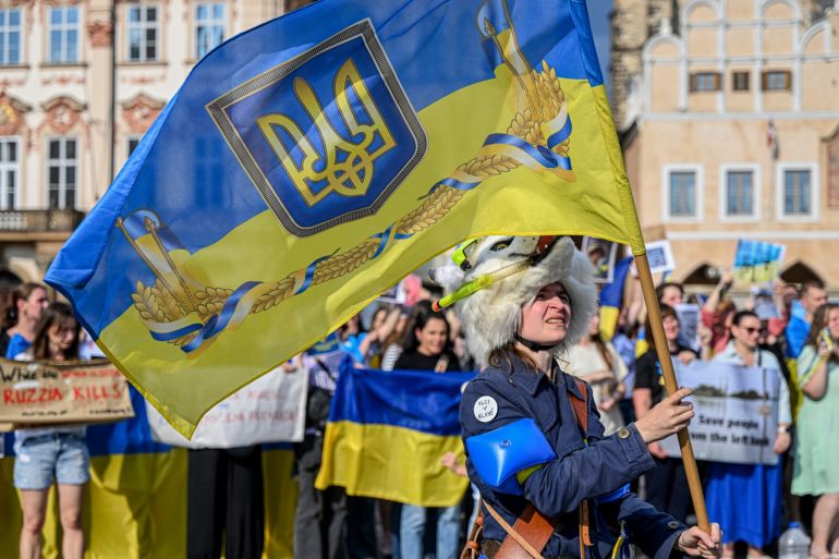 A woman wearing a wolf hat waves a Ukrainian flag during the anti-Russia protest against the destruction of the Russian-controlled Kakhovka dam at the Old Town Square in Prague, Czech Republic