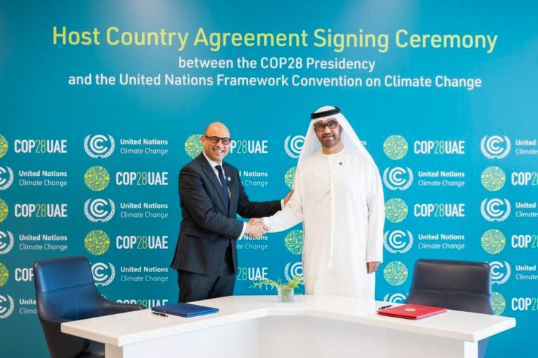 A handout image provided by the United Arab Emirates (UAE) News Agency (WAM) shows the UAE's Minister of Industry and Advanced Technology and COP28 President-Designate Sultan bin Ahmed Al Jaber (R) and the United Nations Framework Convention on Climate Change (UNFCCC) Executive Secretary Simon Stiell during a signing ceremony of the Host Country Agreement in Abu Dhabi, on August 1, 2023