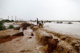 People dig a trench to evacuate muddy flood water along a street, following torrential rain in Saqqai near Omdurman, Sudan