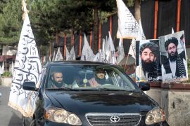 Supporters drive past Taliban flags along a road in Kabul on August 14, 2023.