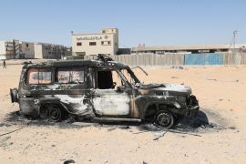 The carcass of a burnt car is pictured following two days of deadly clashes between two rival groups in Libya's capital, on August 16, 2023. - Gun battles between two leading armed groups in Tripoli have killed 27 people and wounded 106, a toll update from the Emergency Medicine Centre said on August 16.