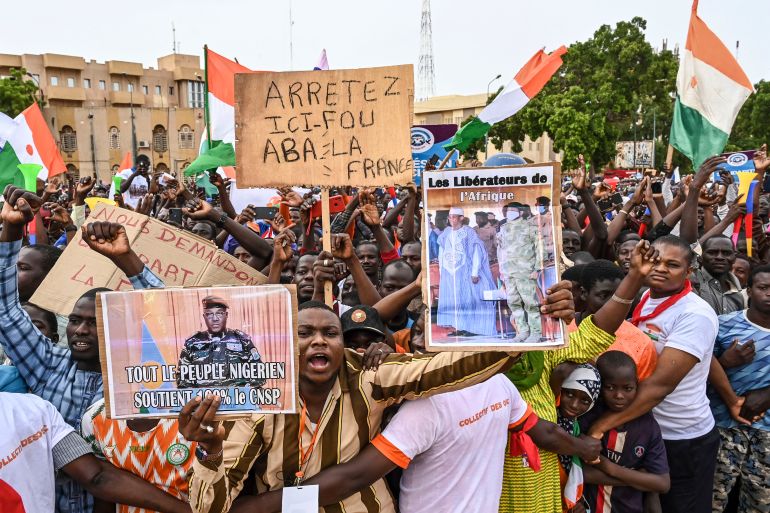 A supporter of Niger's National Concil of Sefeguard of the Homeland (CNSP) holds a placard of Niger's new military ruler, General Abdourahamane Tiani, as they gather at Place de la Concertation in Niamey on August 20, 2023.
