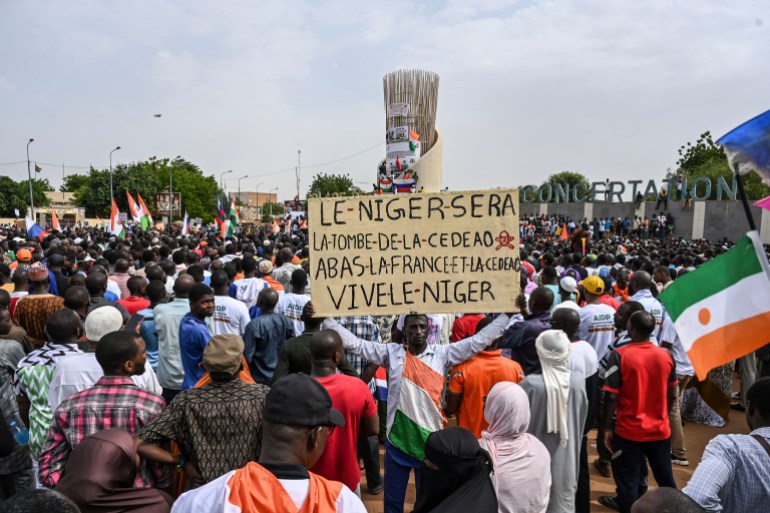 A supporter of Niger's National Concil of Sefeguard of the Homeland (CNSP) fholds a placard of Niger's new military ruler, General Abdourahamane Tiani, as they gather at Place de la Concertation in Niamey on August 20